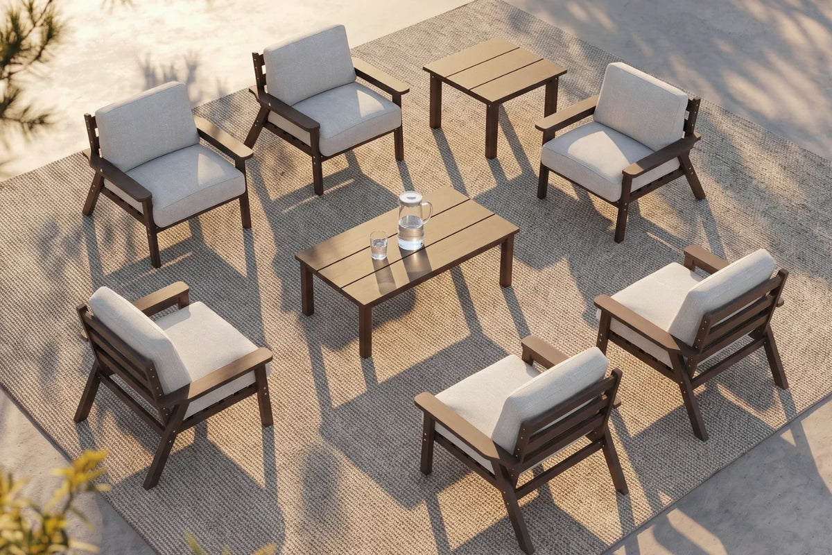 An 8-piece outdoor patio furniture set arranged on a woven rug, featuring six brown armchairs with creamy white cushions, one matching rectangular coffee table, and one matching side table.