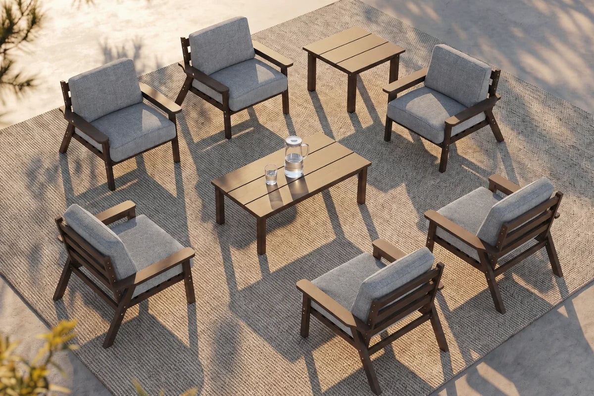 An 8-piece outdoor patio furniture set arranged on a woven rug, featuring six brown wooden armchairs with gray cushions, one matching rectangular coffee table, and one matching side table.