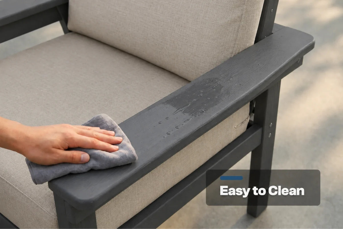 A close-up of a person's hand wiping down a dark gray outdoor armchair with a gray cloth. The chair has creamy white fabric cushions, and a text overlay on the bottom right reads 'Easy to Clean'.