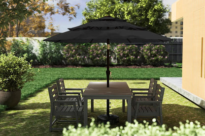 Outdoor patio set with table and chairs under a large black umbrella on a grassy area.