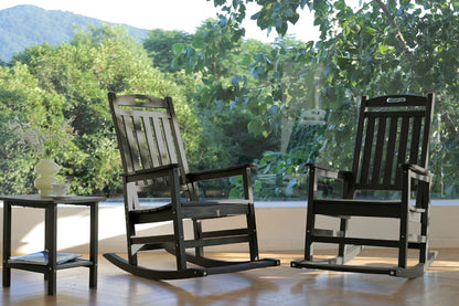 Two black rocking chairs on a wooden floor with a blurred green outdoor background