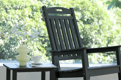 Black outdoor chair with a small table and decorative items on a blurred green background