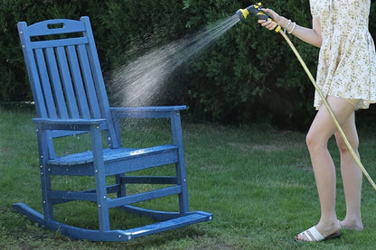 Person using a hose to spray water on a blue outdoor rocking chair.