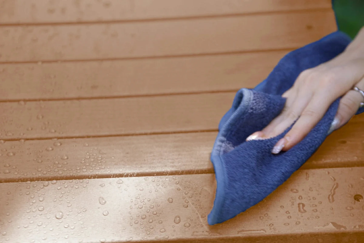 Person cleaning a wooden surface with a blue cloth