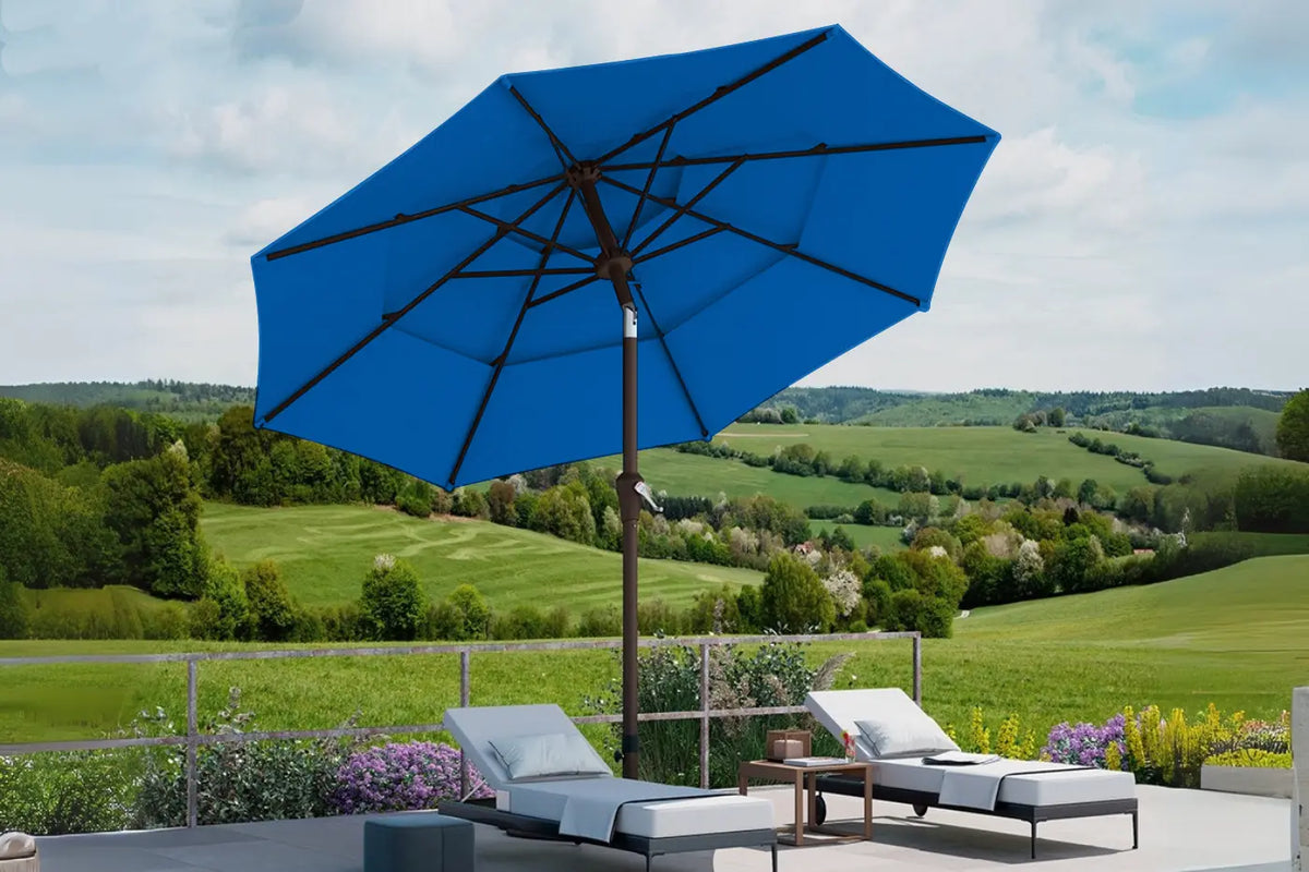 Blue patio umbrella on a stand with a scenic background of green fields and trees.