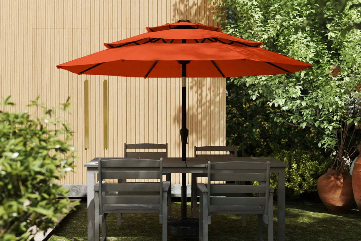 Outdoor patio set with a large red umbrella in a garden setting.