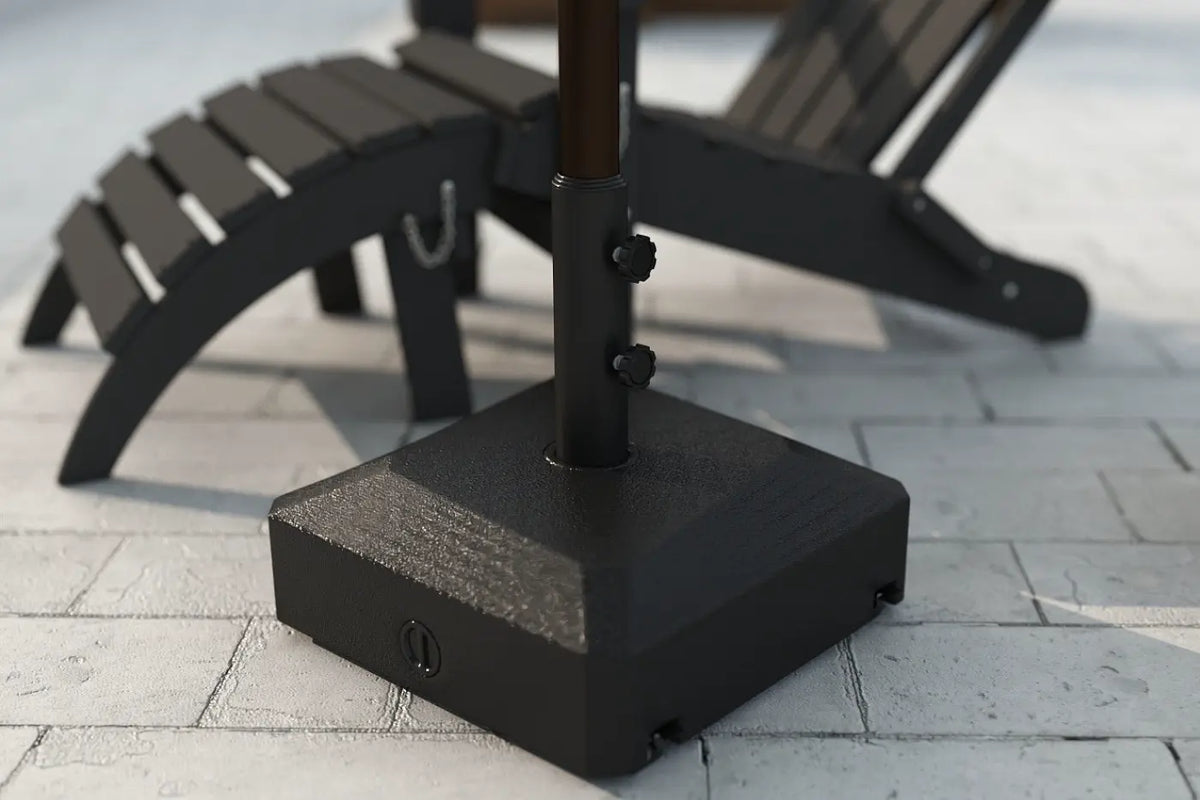 Black patio umbrella stand on a concrete surface with a blurred lounge chair in the background.