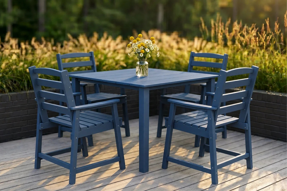 Blue outdoor table with four matching chairs on a wooden deck, surrounded by greenery.