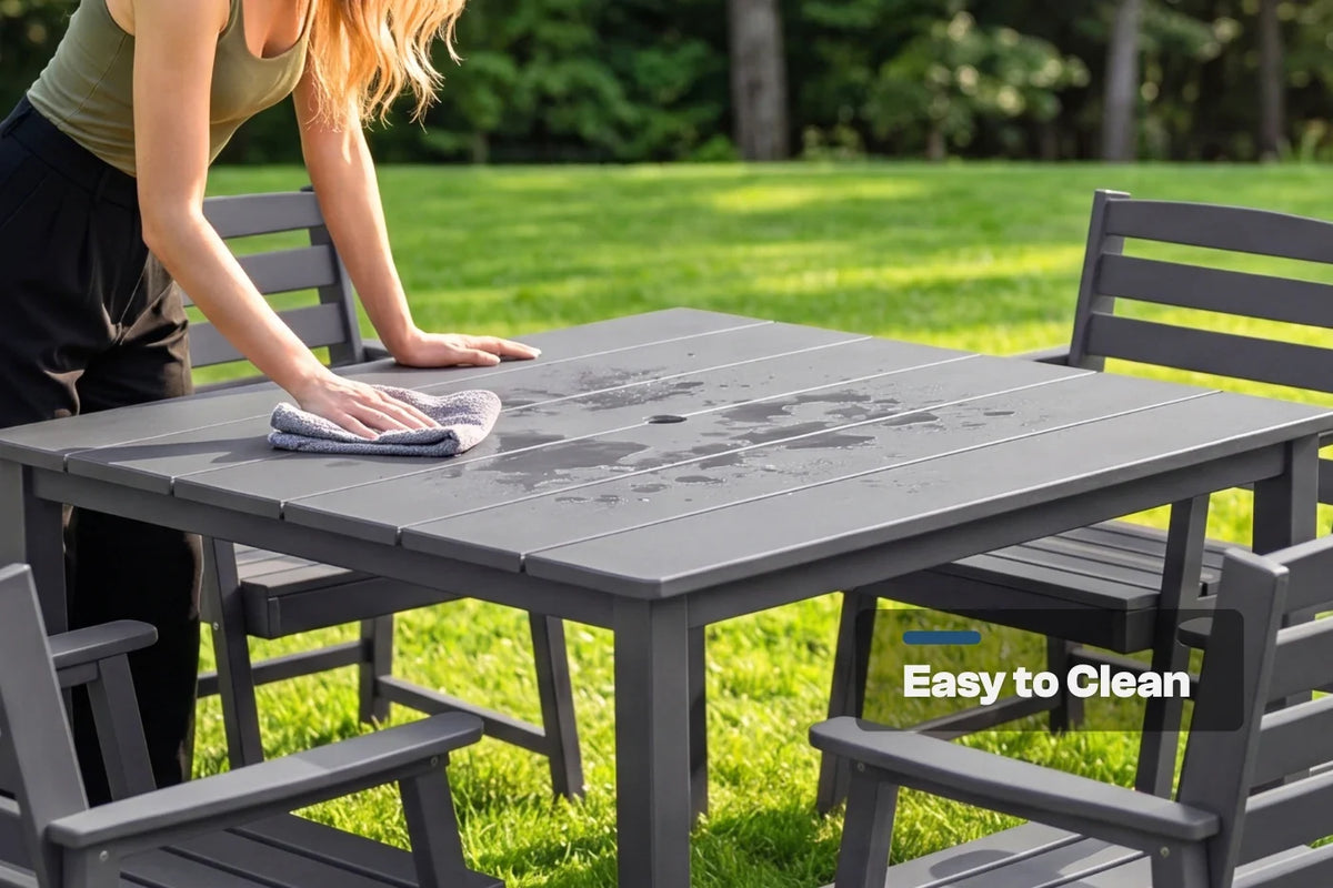 Person cleaning a gray outdoor table with chairs in a grassy area, emphasizing ease of cleaning.