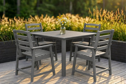 Gray Outdoor dining set with a table and four chairs on a wooden deck, surrounded by greenery.