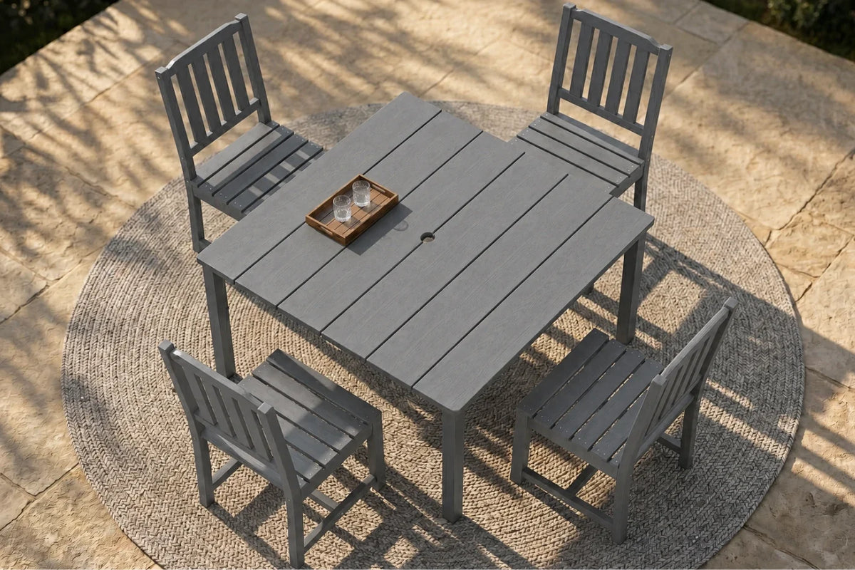 Outdoor furniture set with a gray table and 4 armless chairs on a stone patio.