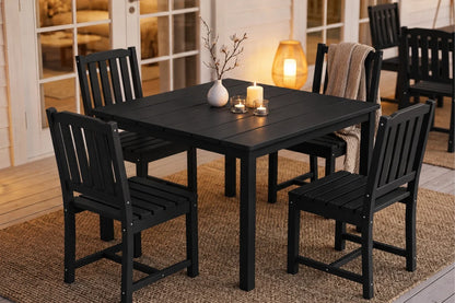 Black dining table with four armless chairs in a room with a rug and decorative items.