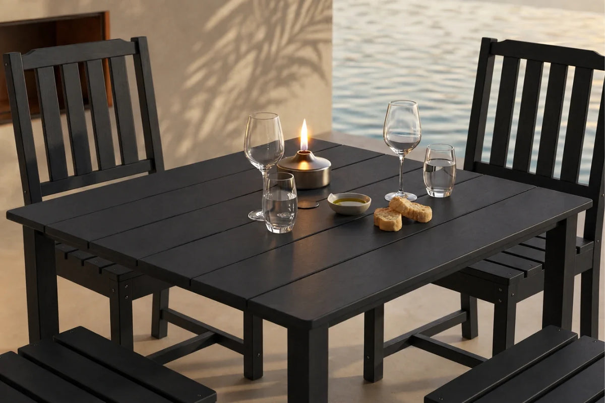 Black outdoor table with 4 armless chairs and glasses by a body of water