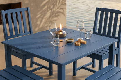 Blue outdoor table with 4 armless chairs set against a water background