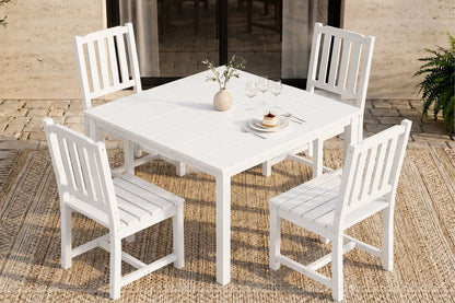 White outdoor dining table with four matching armless chairs on a textured patio surface.