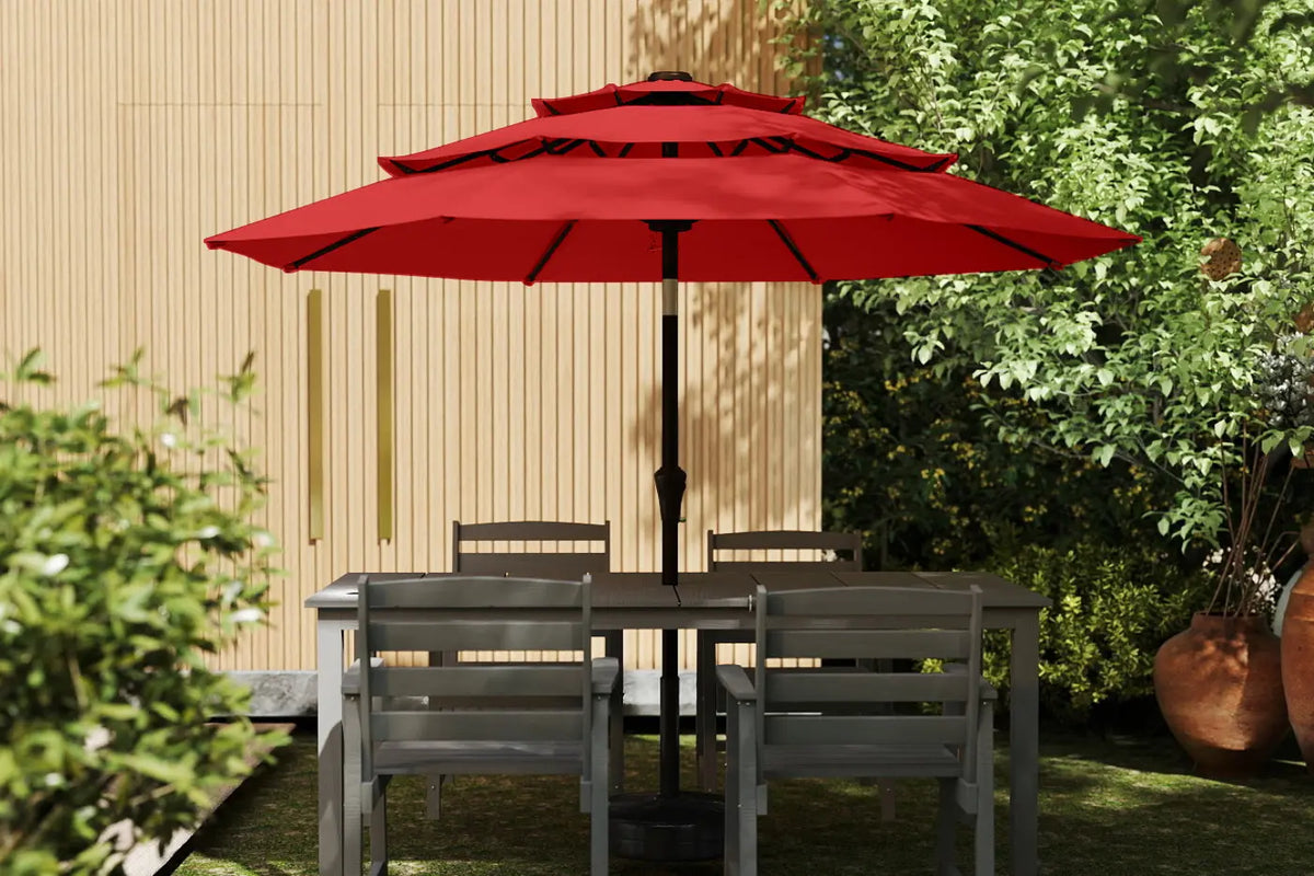 Outdoor patio set with a red umbrella and gray chairs in a garden setting.