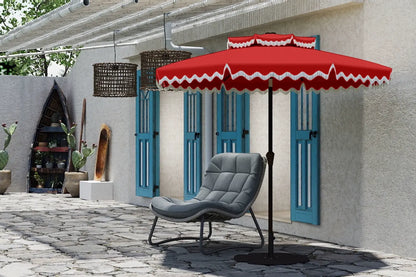 Red and white striped patio umbrella over a gray chair on a stone patio.