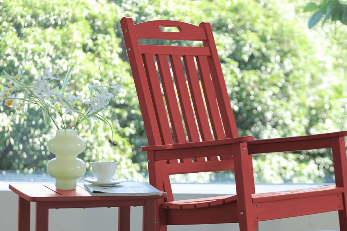 Red wooden chair with a small table and decorative items on a blurred green outdoor background