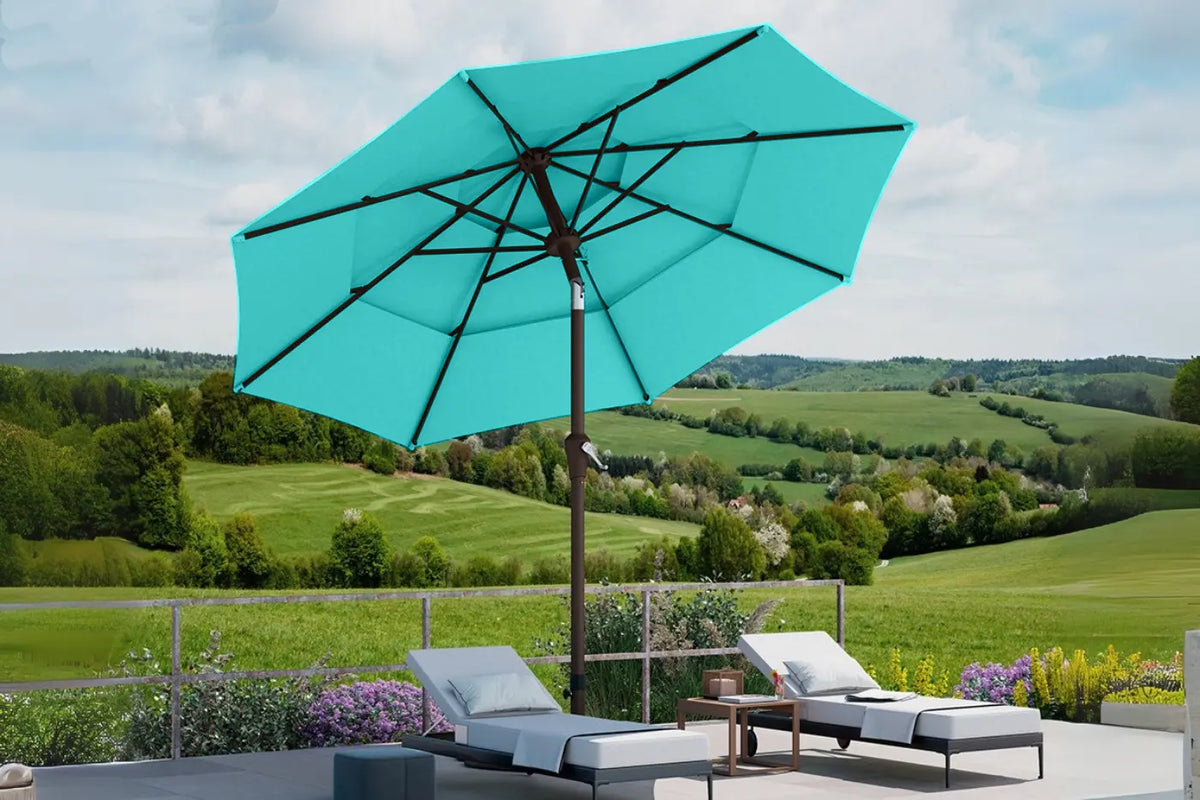 Turquoise patio umbrella with lounge chairs and a scenic view of green fields.