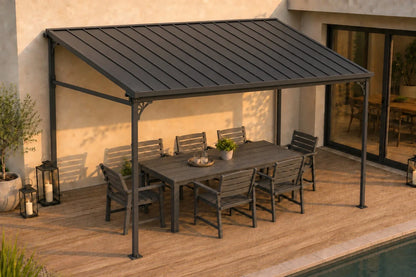 A dark gray wall-mounted hardtop gazebo, supporting a matching outdoor dining table and chairs on a wooden deck next to a swimming pool.