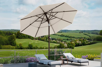Beige patio umbrella with lounge chairs and a scenic view of green fields and hills.