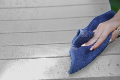 Person cleaning a wooden surface with a blue cloth