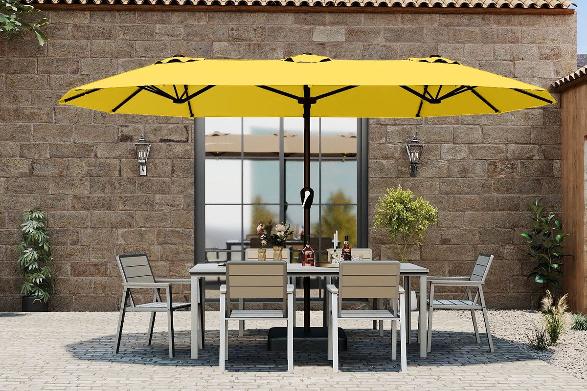 Outdoor patio set with a large yellow umbrella against a stone wall.