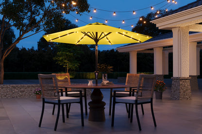 Outdoor patio set with a yellow umbrella and string lights at night.