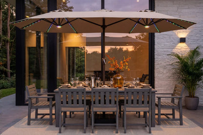 Outdoor dining set with a rectangular gray slat table, six matching chairs, a large beige patio umbrella with RGB LED, and a modern glass-walled patio at dusk.