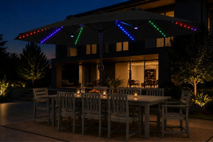 Outdoor patio umbrella with colorful RGB LED string lights in blue, green, red, and purple, shading a dining table and chairs at dusk.