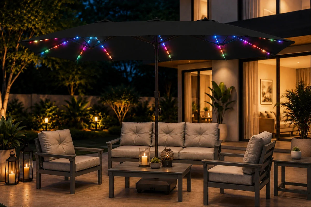Outdoor patio furniture set under a large black patio umbrella decorated with multicolor RGB LED string lights, set in a modern backyard at night.