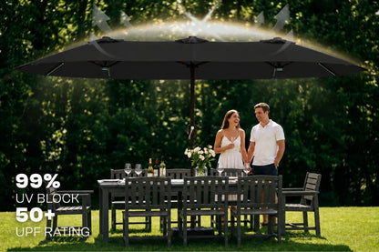 A large black outdoor patio umbrella with a built-in sprinkler system, shown in a garden setting with a couple standing underneath. 