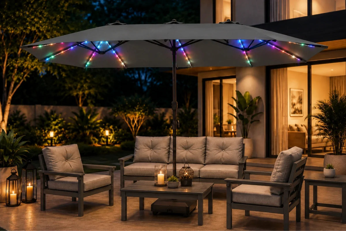 Outdoor patio furniture set under a large dark gray patio umbrella with colorful RGB LED string lights, shown at night in front of a modern house. The set includes a sofa, two armchairs, a coffee table, and a side table on a paved deck.