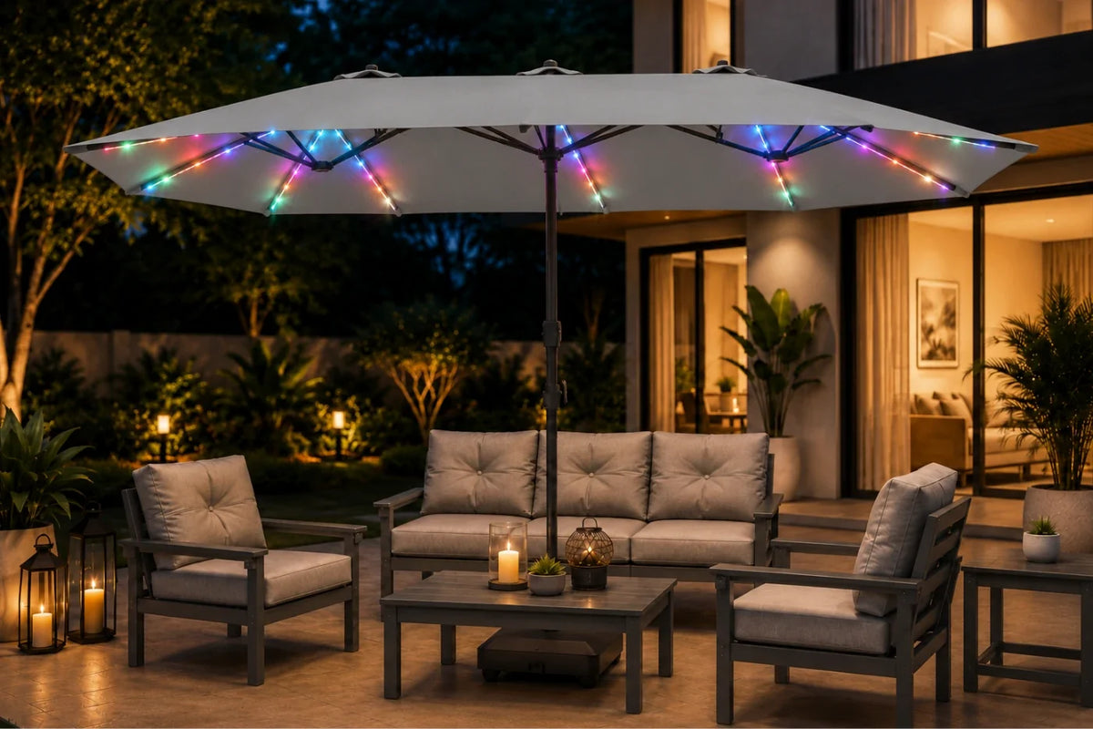 Outdoor patio furniture set under a large gray patio umbrella with multicolor RGB LED string lights, shown at night on a tiled deck in front of a modern house.