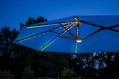 A large indigo blue patio umbrella with illuminated RGB LED light strips glowing blue and green, shown against a twilight sky with dark trees in the background.