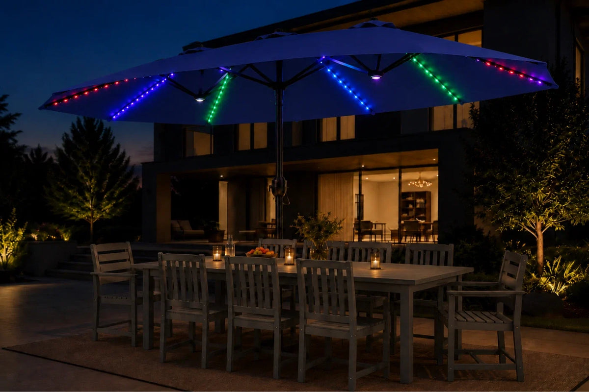 A large navy blue patio umbrella with colorful RGB LED string lights in blue, green, red, and purple, shading an outdoor dining table and chairs at dusk.