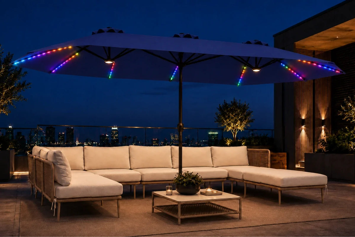 Outdoor patio furniture set with a large navy blue patio umbrella decorated with multicolor RGB LED string lights, a beige sectional sofa, and a matching coffee table at dusk.