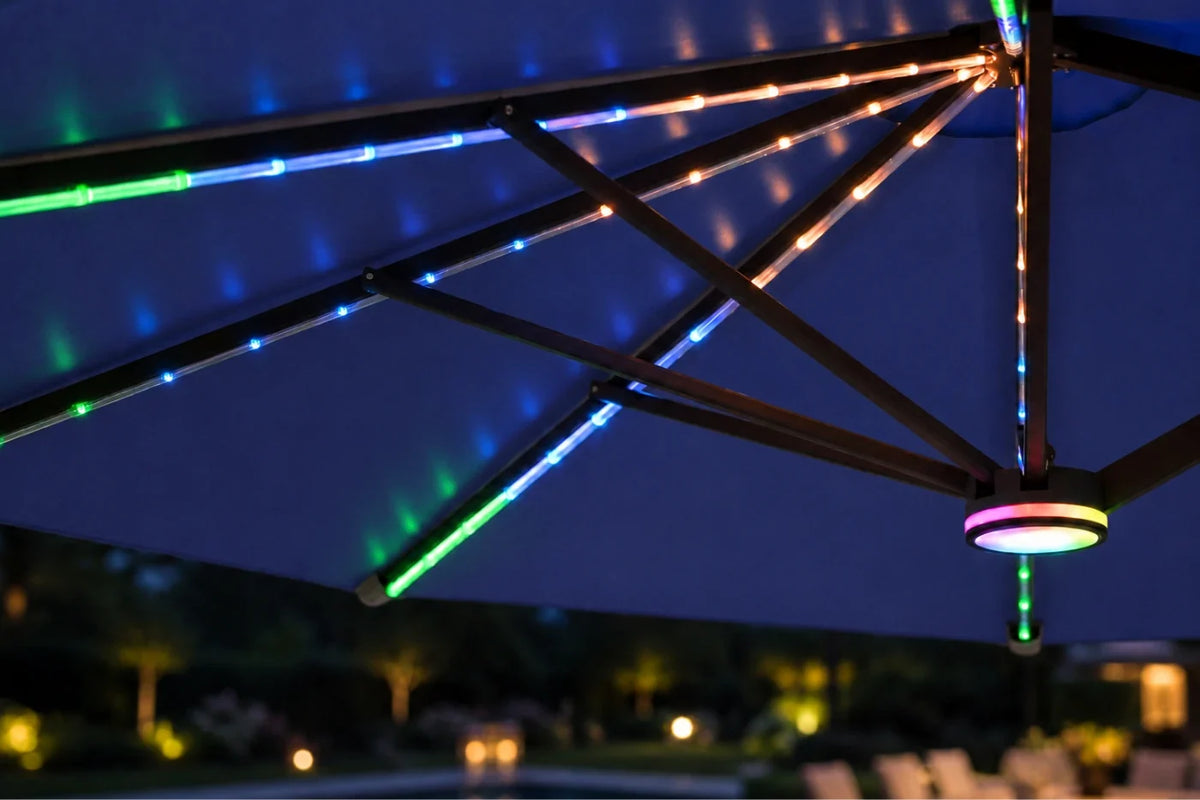 Multicolor RGB LED string lights running along the metal support beams of a large patio umbrella at night, with a circular light fixture glowing at the bottom right.