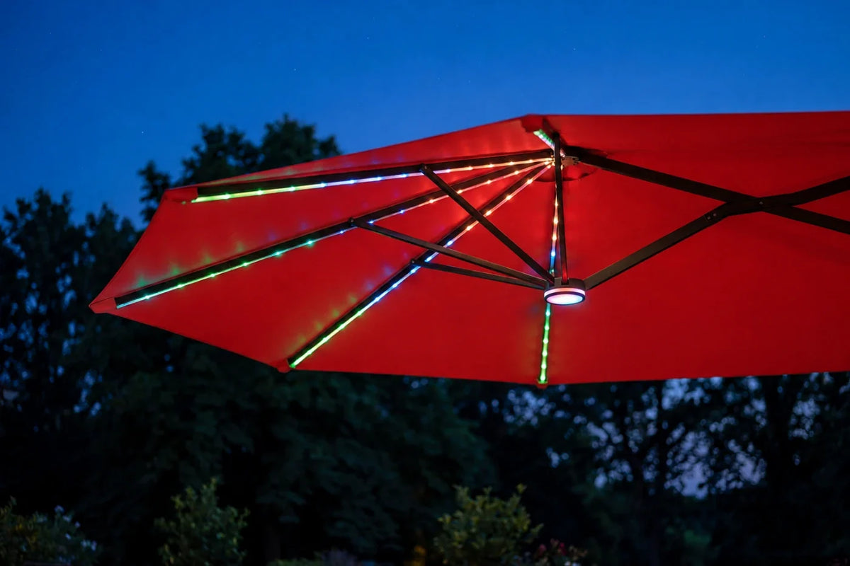 A red patio umbrella with integrated RGB LED lighting glowing along the ribs, photographed outdoors against a dark blue evening sky and silhouetted trees.