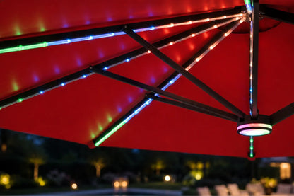 Red patio umbrella with multicolor RGB LED string lights glowing along the canopy and frame, photographed at night with a blurred outdoor background.