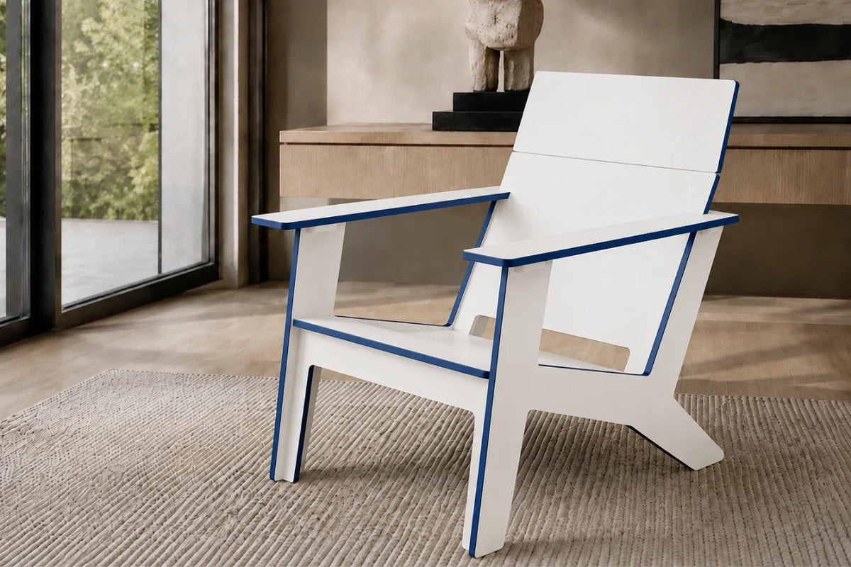 A white modern poly Adirondack chair with blue trim, positioned on a textured beige rug in a contemporary indoor setting with a glass window and a console table in the background.