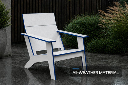 A modern poly Adirondack chair with a white slatted seat and armrests outlined in blue, shown on a wet stone patio with shrubs and a dark fence in the background. A text overlay at the bottom right reads 'All-WEATHER MATERIAL'.
