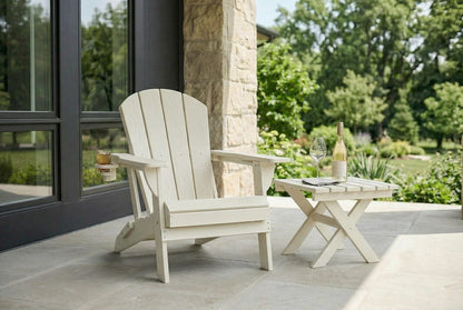 White Adirondack chair on a patio with a small table and wine bottle.