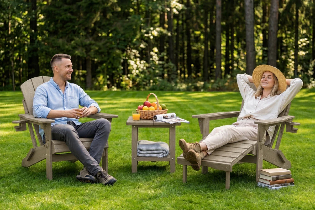 A man and a woman relax in light brown Adirondack chairs on a grassy lawn with a small table between them, set against a dense green forest background.