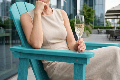 Woman sitting on a aruba blue chair holding a glass of champagne with a cityscape background