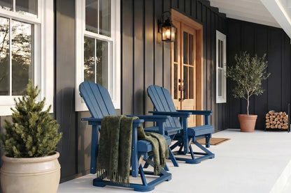 Two navy blue Adirondack chairs on a porch with a black house and potted plants.