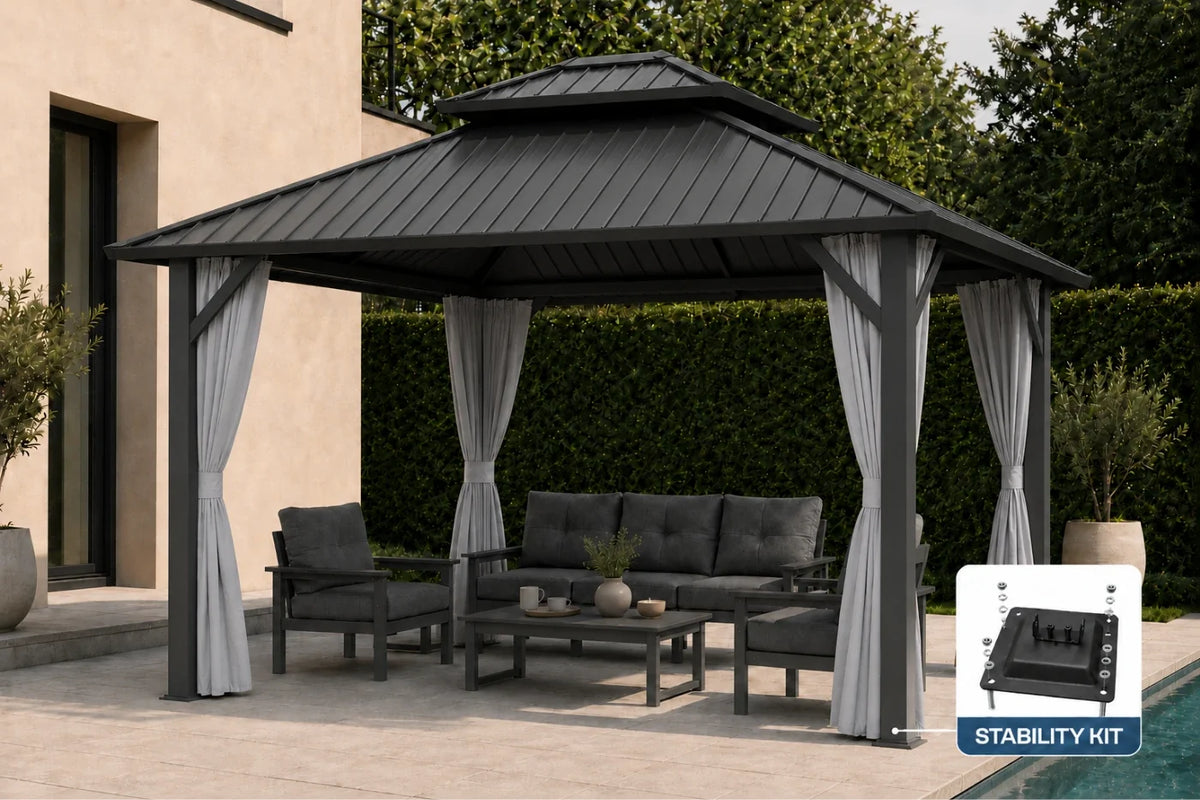 A dark gray outdoor patio gazebo with gray curtains, furnished with a matching sofa, chairs, and coffee table. The gazebo is set on a paved patio next to a house wall and hedge, with a small inset showing a stability kit accessory.