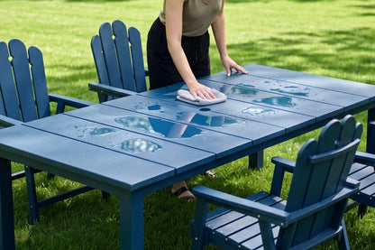 Person cleaning a navy blue outdoor table with 4 chairs on a grassy area