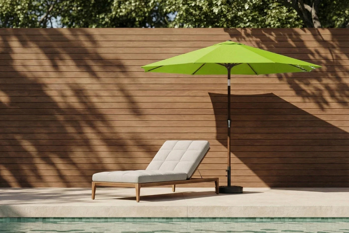 Green patio umbrella and lounge chair by a poolside with wooden wall background