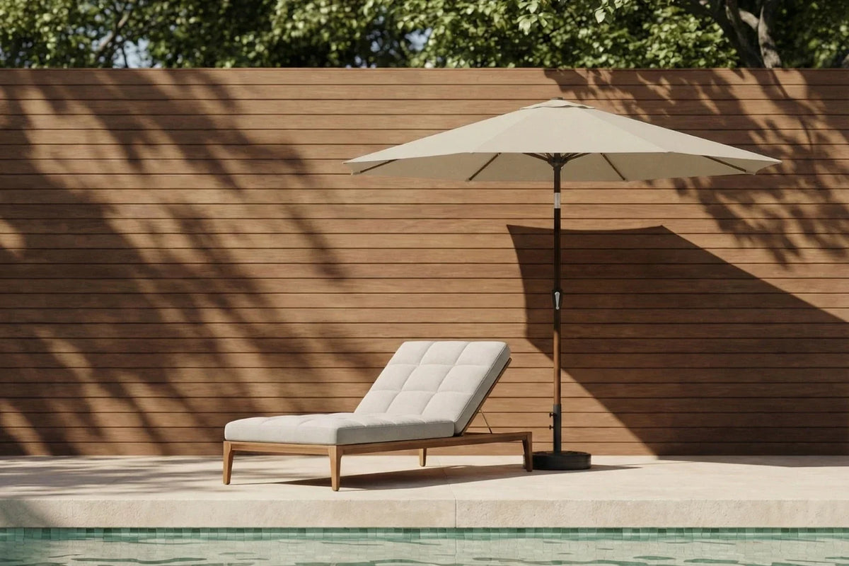 Beige lounge chair with umbrella by a poolside against a wooden wall